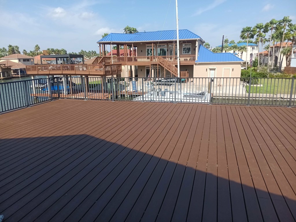 Waterfront deck with black railings overlooking a canal and custom home